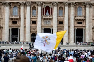 The Vatican flag flies because of people gathered to watch the conclusion